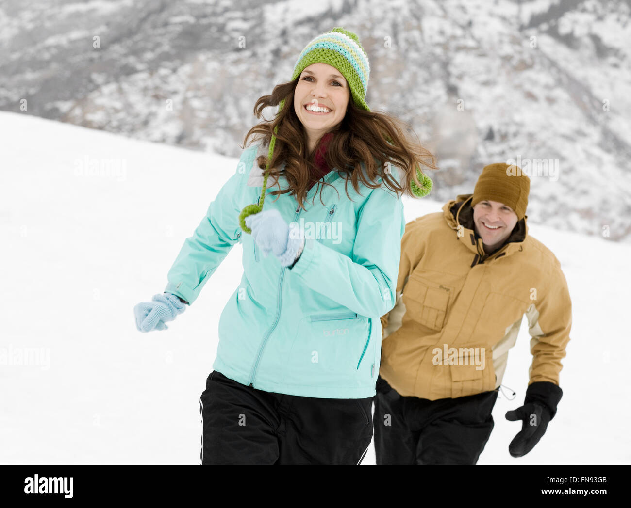 Due persone, una giovane, nel bel mezzo delle montagne innevate, che si rincorrono. Foto Stock