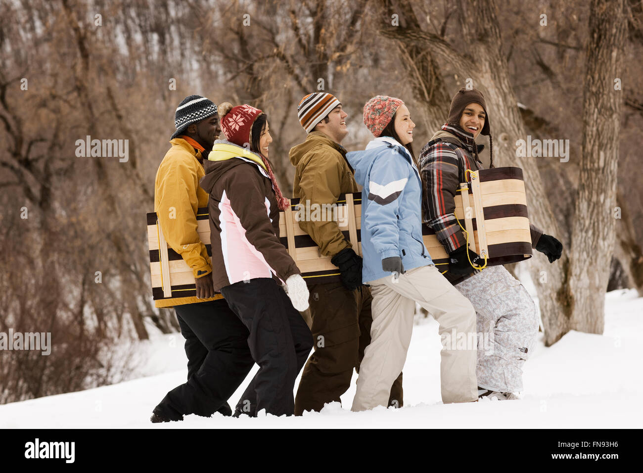 Cinque giovani che porta una slitta di legno attraverso la neve. Foto Stock