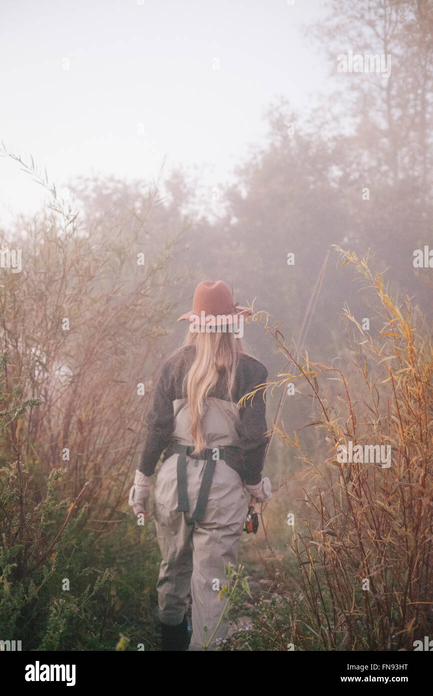 Una donna in un cappello e vestiti caldi, portante una canna da pesca. Foto Stock