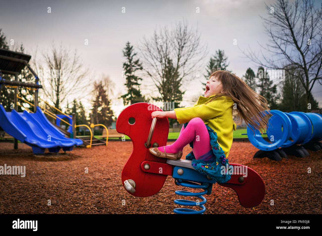 Ragazza seduta sulla corsa di primavera nel parco giochi Foto Stock