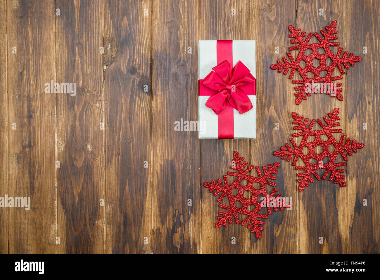 Regalo bianco seta rossa avvolgere per evento di festa con il simbolo del fiocco di neve su sfondo di legno Foto Stock