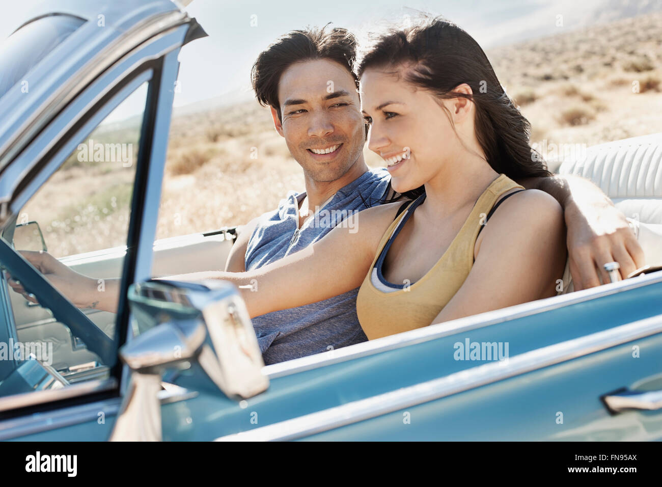 Una coppia giovane, l uomo e la donna in un pallido convertibile blu sulla strada aperta Foto Stock