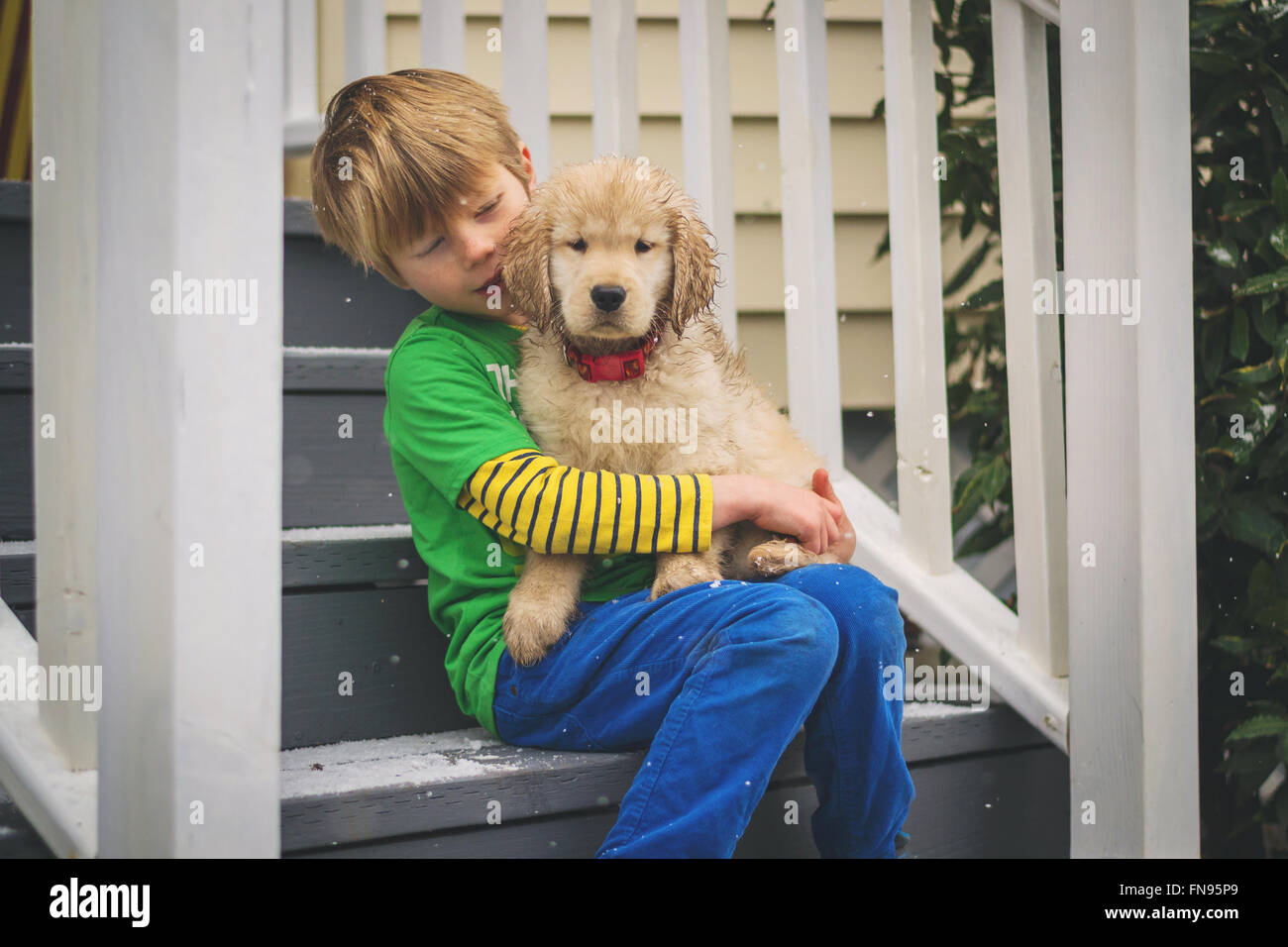 Ragazzo seduto sul patio passi con il golden retriever cucciolo di cane Foto Stock