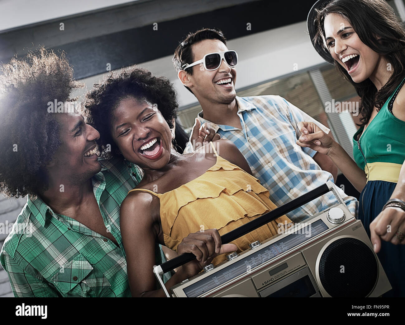 Quattro amici con un grande lettore musicale portatile, avente una parte. Foto Stock