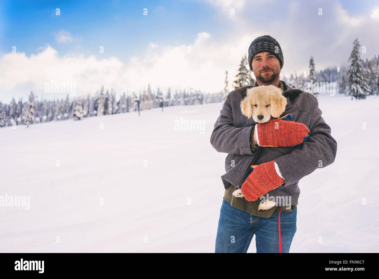 Uomo con il golden retriever cucciolo di cane nel suo cappotto Foto Stock