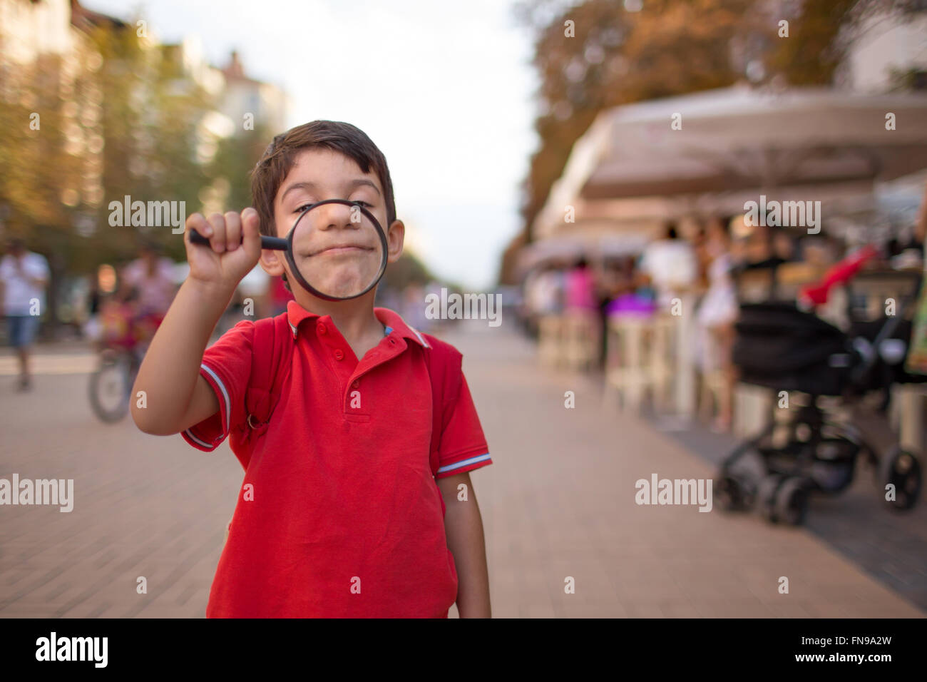 Giovane ragazzo che sorride attraverso la lente di ingrandimento, sofia, Bulgaria Foto Stock