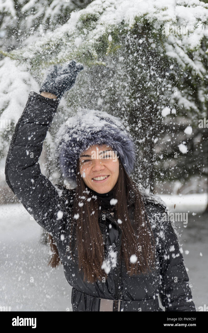 Donna sorridente gettando la neve in aria Foto Stock