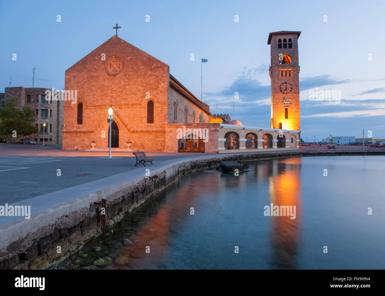 La città di Rodi, rodi, Egeo Meridionale, Grecia. Gli illuminati cattedrale ortodossa si riflette nel porto di Mandraki, alba. Foto Stock