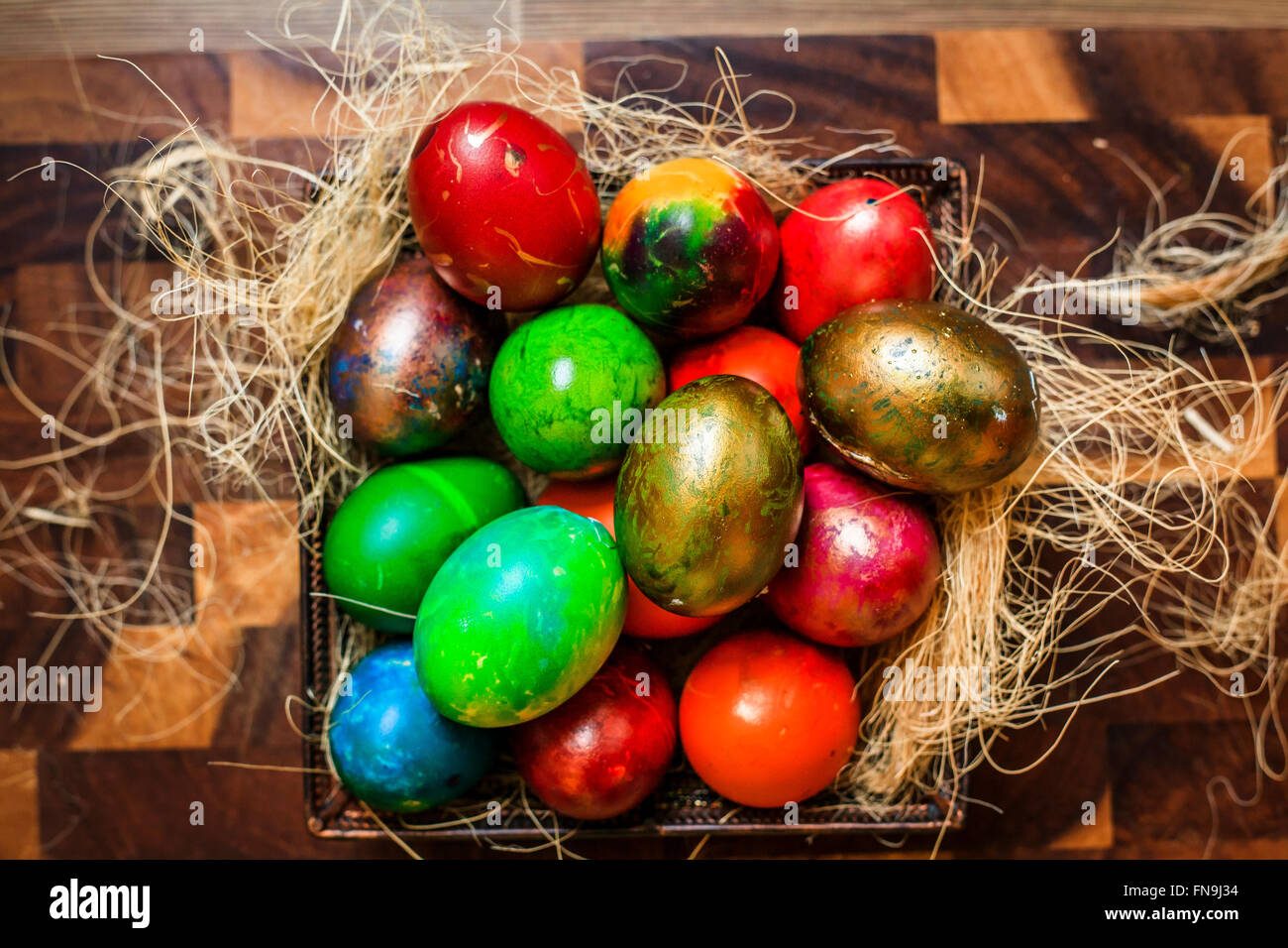 Colorate le uova di Pasqua all'interno di un nido sul tavolo della cucina Foto Stock