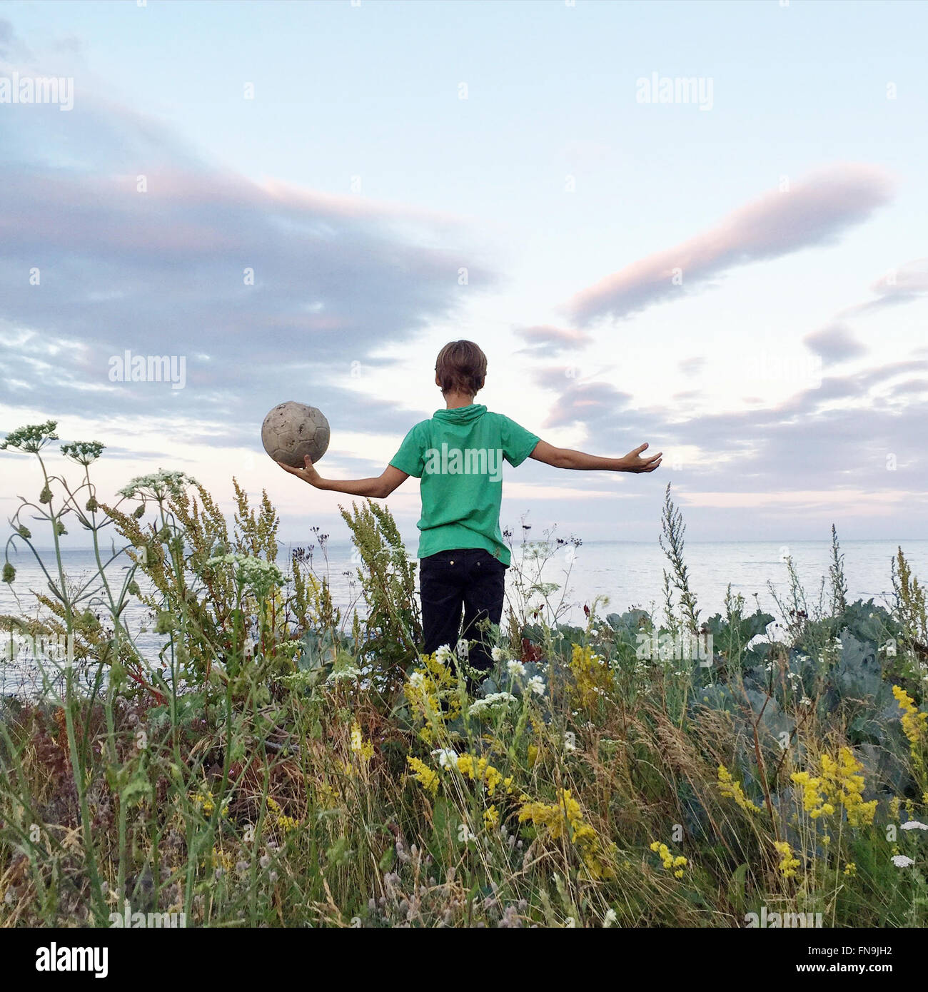 Ragazzo in piedi in un campo tenendo un calcio, Ringshaug, Tonsberg, Norvegia Foto Stock