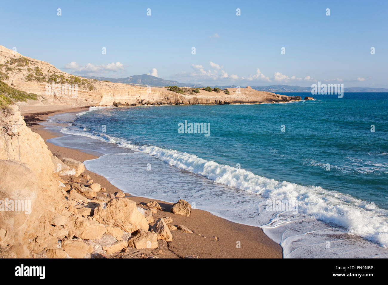 Monolithos, Rodi, Egeo Meridionale, Grecia. Onde che si infrangono sulla spiaggia sabbiosa a Cape Fourni. Foto Stock