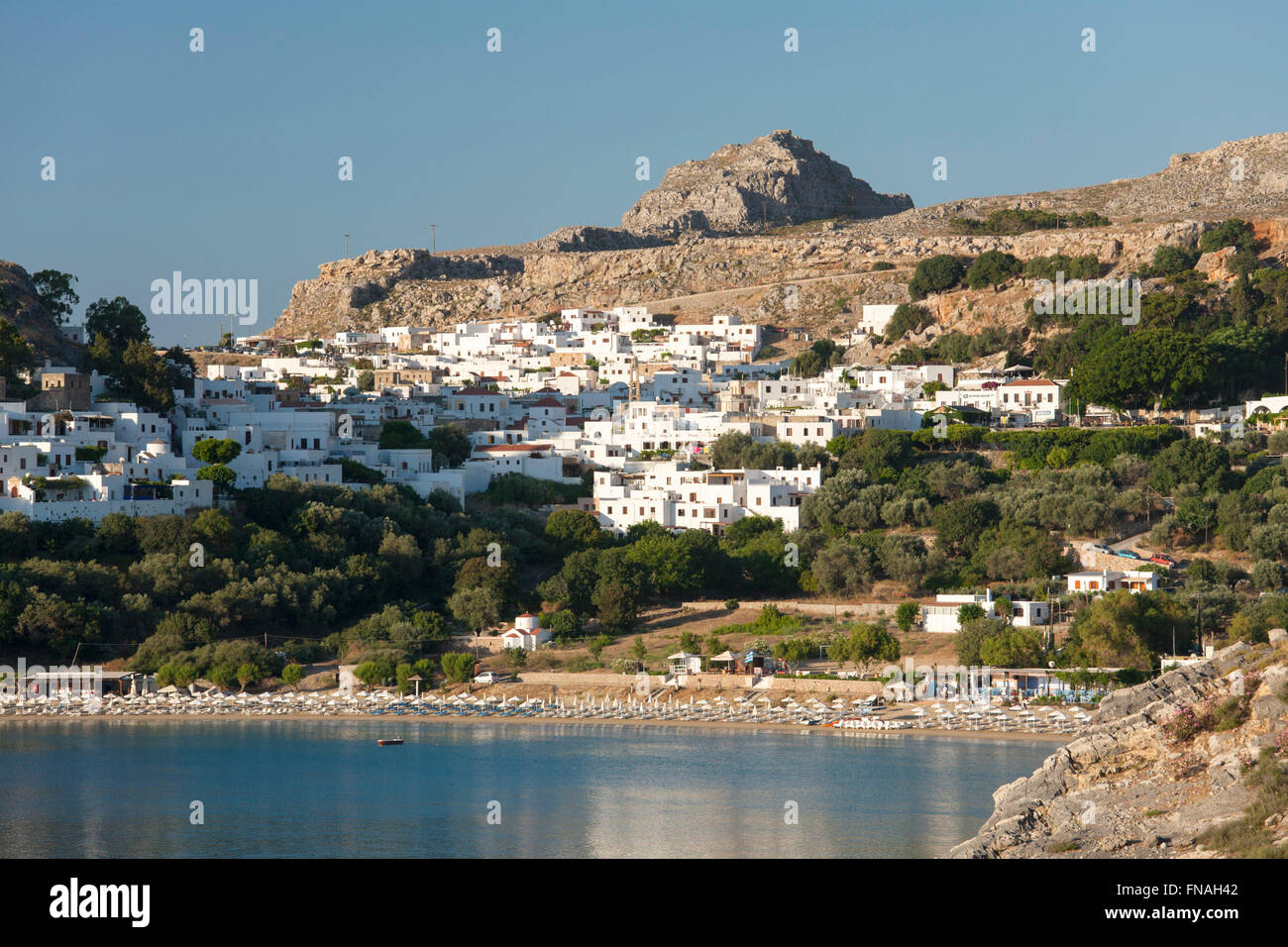 Lindos, Rodi, Egeo Meridionale, Grecia. Vista del villaggio dalla collina sopra tranquilla baia di Lindos. Foto Stock