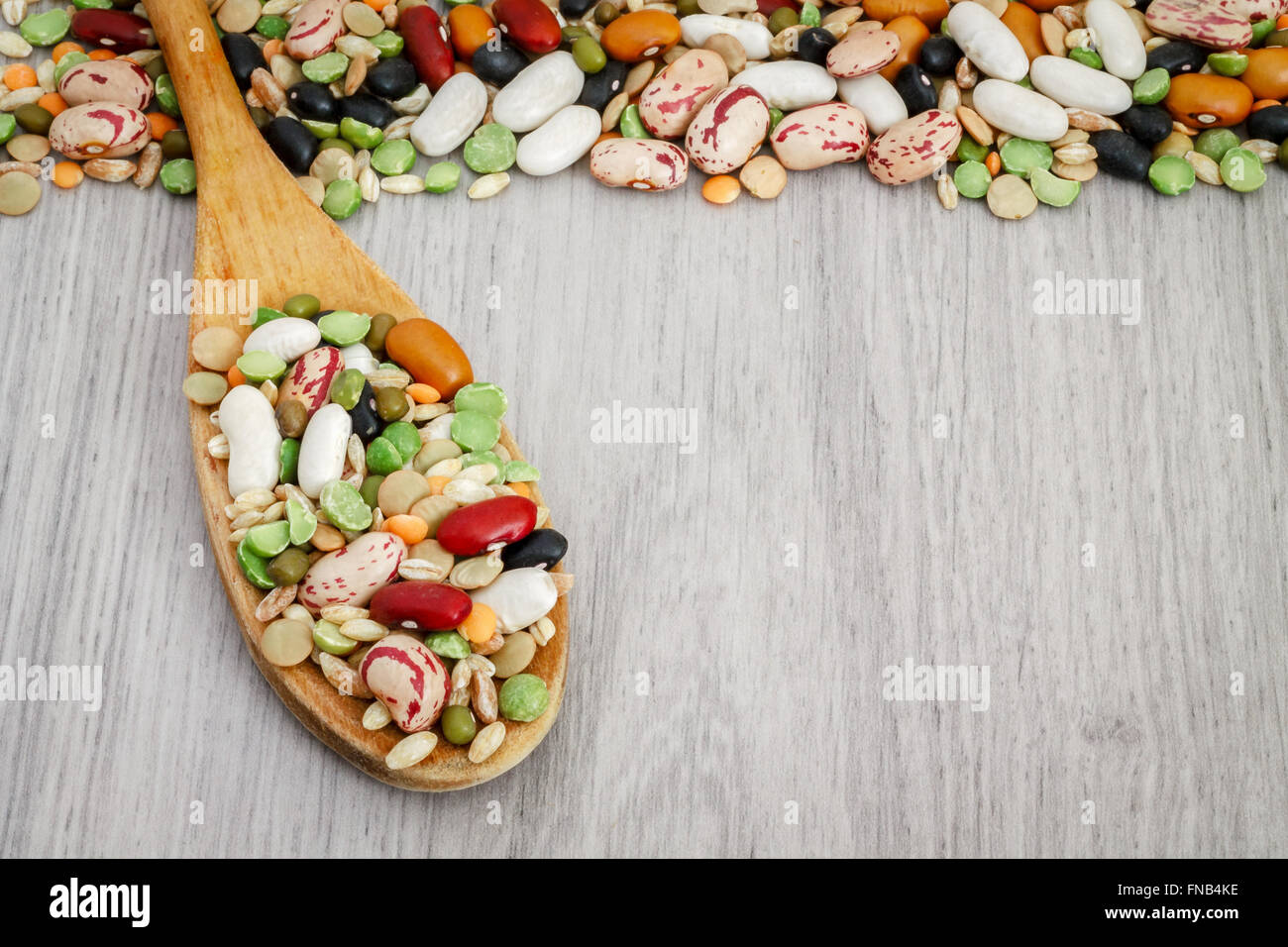 Misto di legumi secchi e cereali in cucchiaio di legno sul grigio Sfondo di legno. Spazio di copia Foto Stock