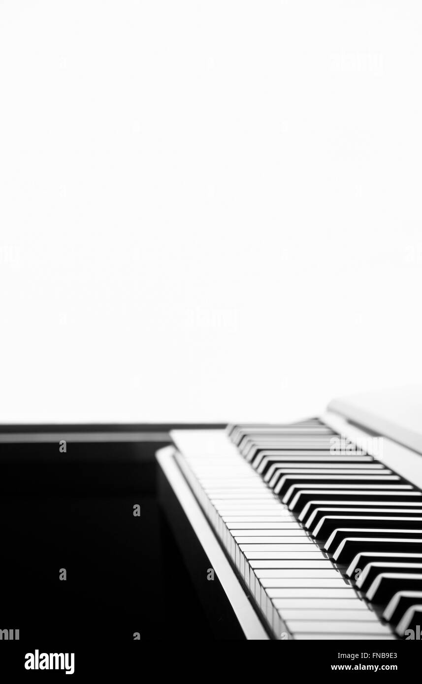 In bianco e nero il fuoco selettivo tastiera di pianoforte sparato da un angolo basso e retroilluminato con uno sfondo bianco Foto Stock