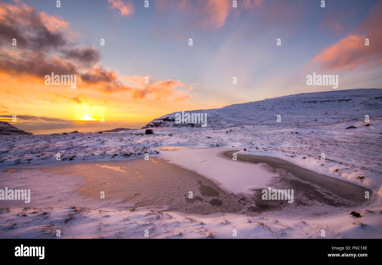 Serata fantastica paesaggio incandescente dalla luce del sole. Drammatica scena invernale. La neve e il tramonto. Isole Faerøer, Danimarca,l'Europa Foto Stock