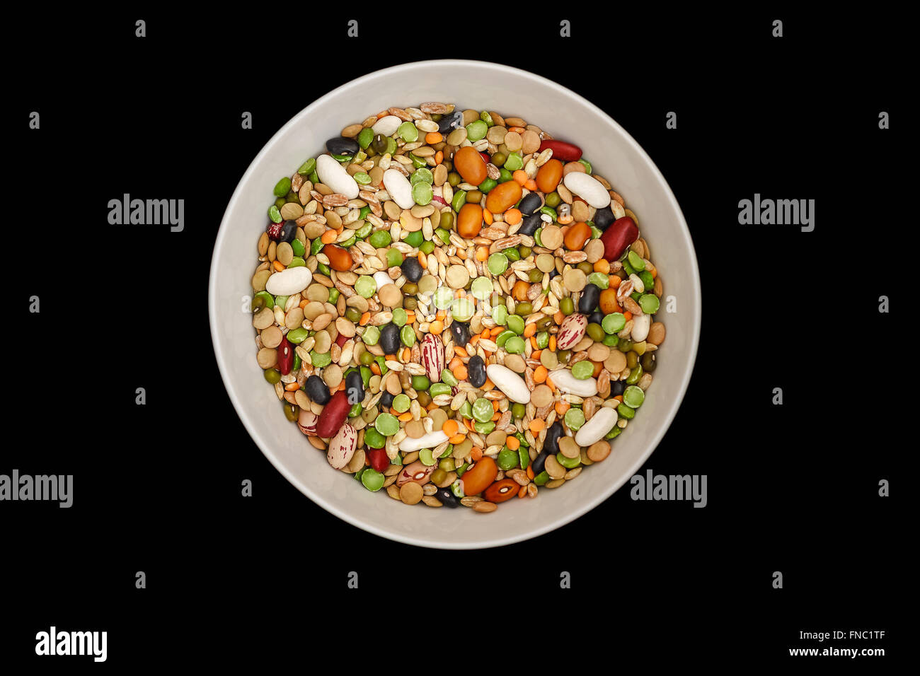 Misto di legumi secchi e cereali nella ciotola bianco su sfondo nero. Vista superiore Foto Stock