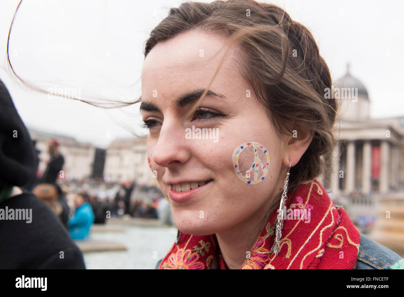 Una giovane donna con un segno di pace dipinta sulla guancia visto durante l'anti-nucleare protesta in Trafalgar Square, Londra, 2016. Foto Stock