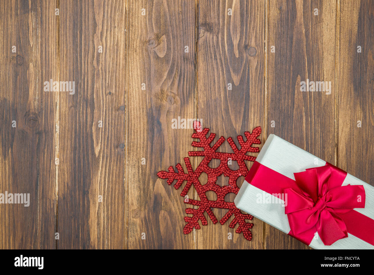 Regalo bianco seta rossa avvolgere per evento di festa con il simbolo del fiocco di neve su sfondo di legno Foto Stock