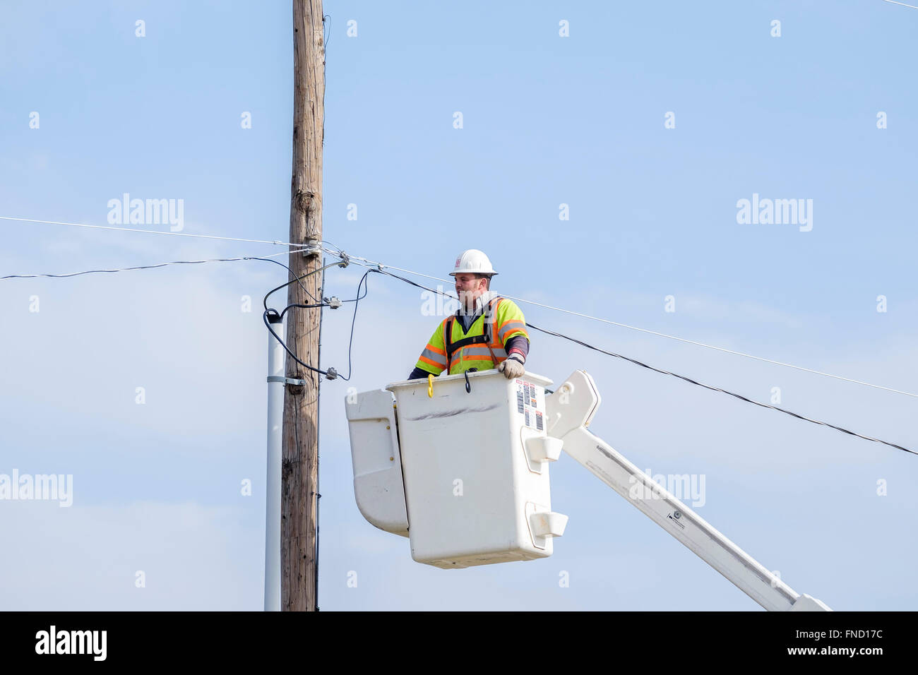 Un lineman viene abbassata al suolo in un sollevamento benna dopo la riparazione di una linea elettrica. Oklahoma City, OK, Stati Uniti d'America. Foto Stock
