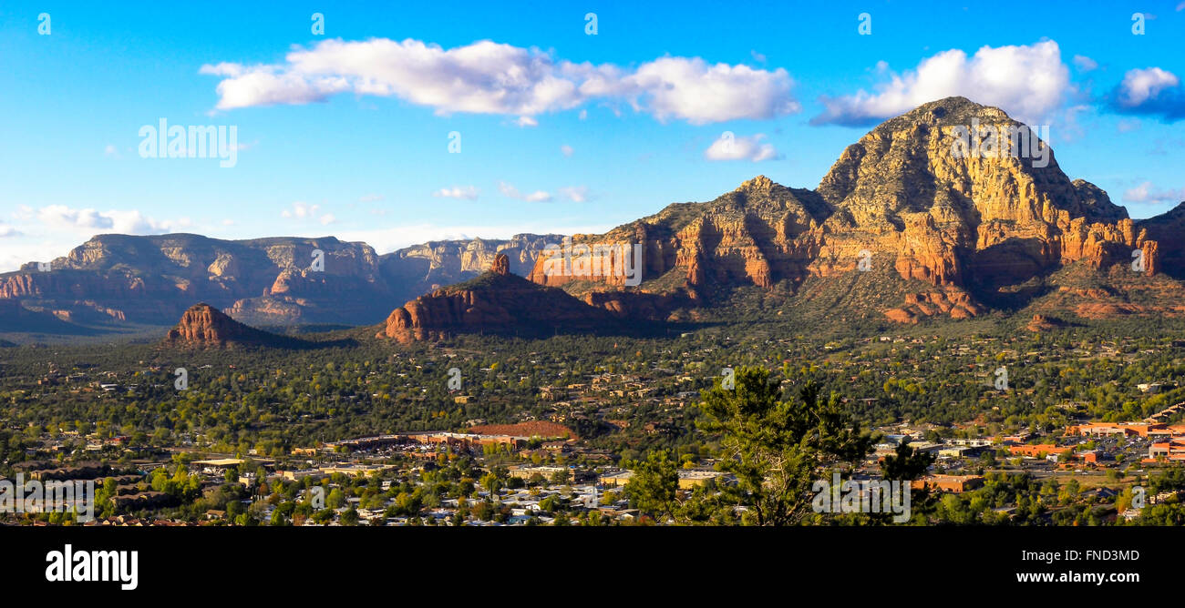 Affacciato a Sedona in Arizona, montagne colorate, città sotto nella valle verde sotto il cielo blu con soffici nuvole. Foto Stock