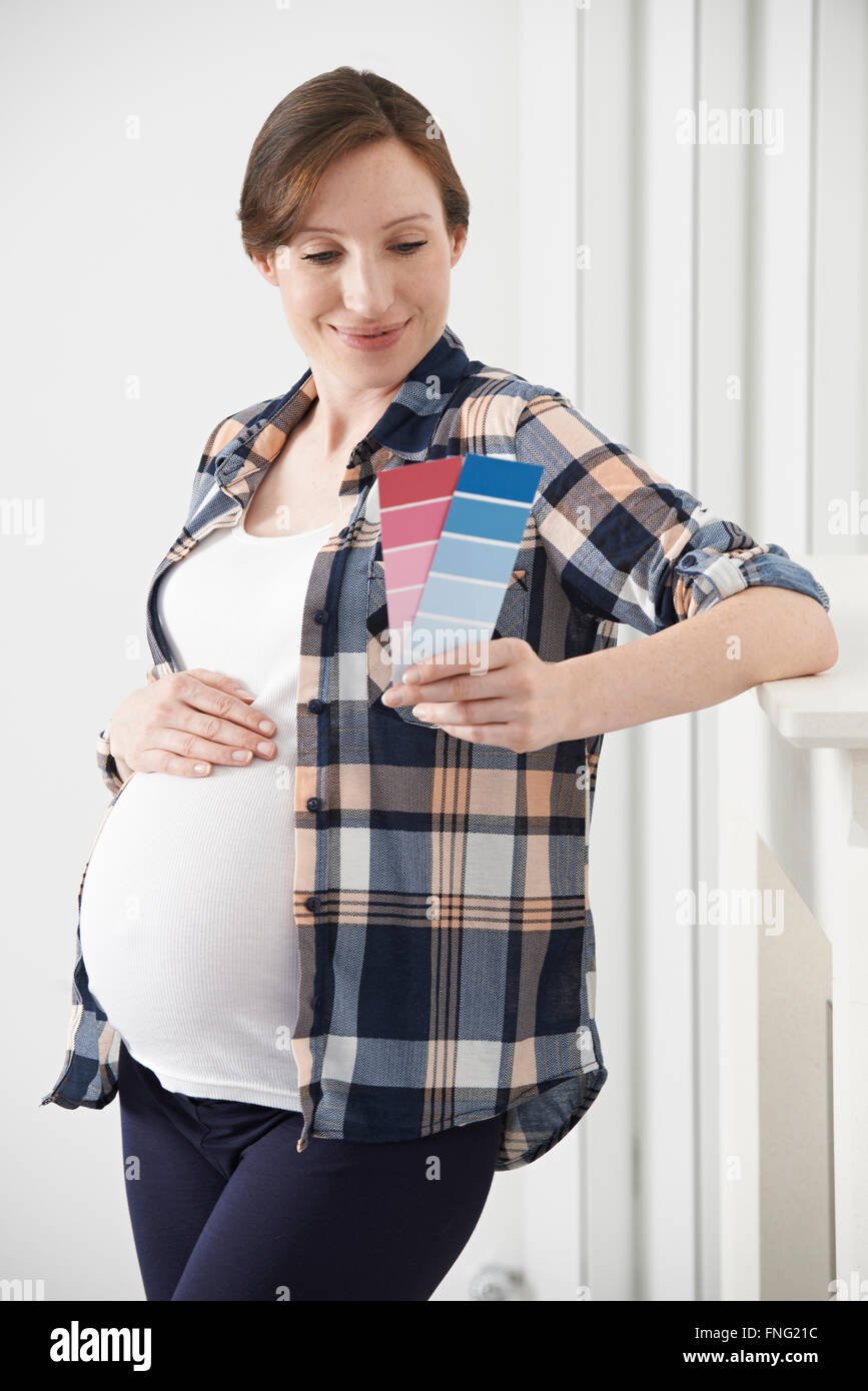 Donna incinta scegliendo la combinazione di colori per la stanza del bambino Foto Stock