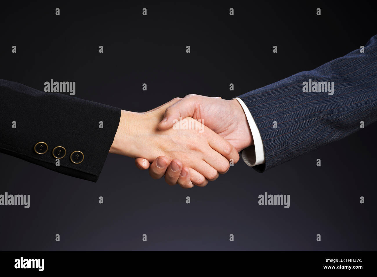 Trattare, business handshake. Donna e uomo mano su uno sfondo grigio. Foto Stock