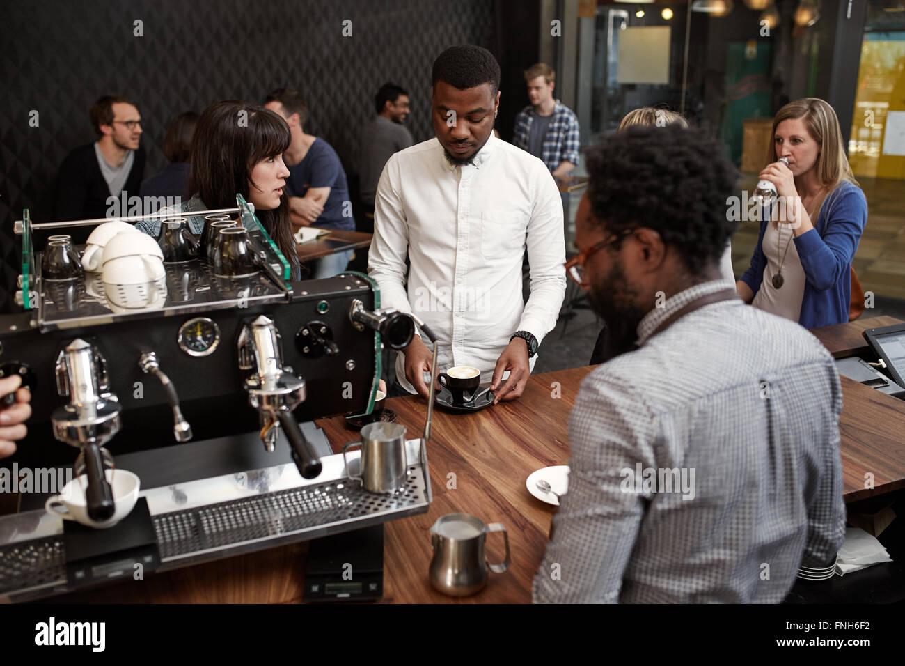 L'uomo africano con cappuccino al banco della moderna caffetteria Foto Stock