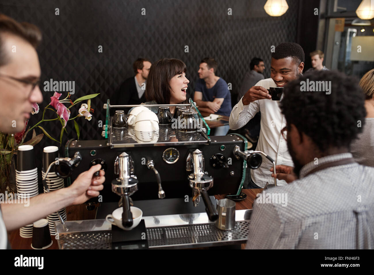 Donna che ride con African amico al bancone del negozio di caffè Foto Stock
