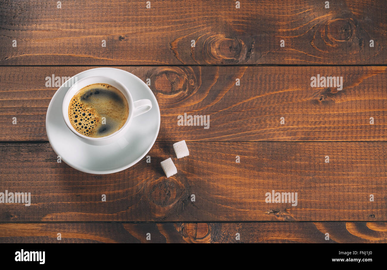 Una bella tazza di caffè con due zollette di zucchero i cubi su vecchio sfondo di legno Foto Stock