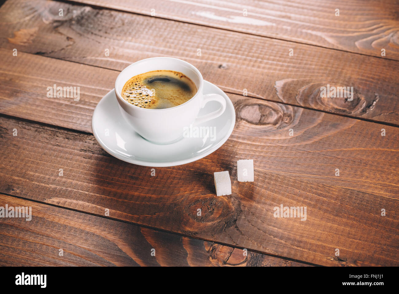 Una bella tazza di caffè con due zollette di zucchero i cubi su vecchio sfondo di legno Foto Stock