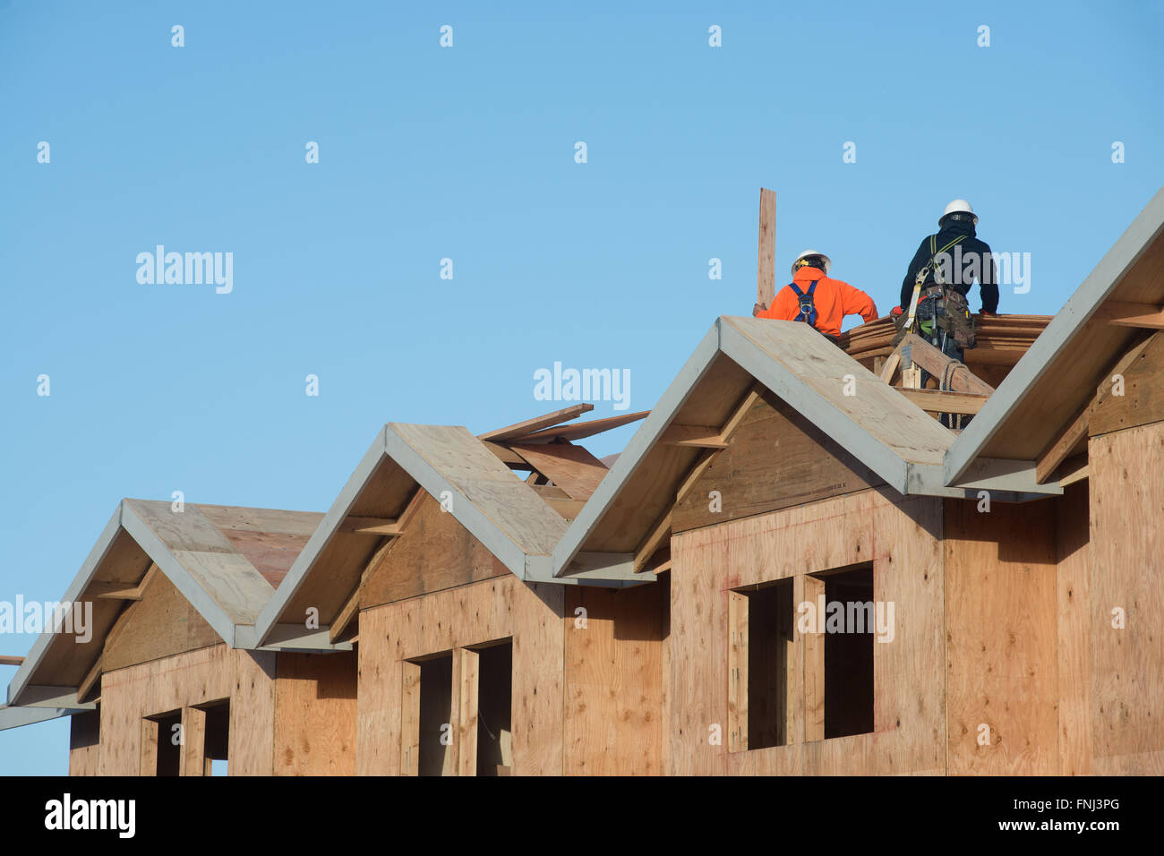 Due lavoratori applicare il legno compensato per la parte superiore di un appartamento in costruzione. Foto Stock