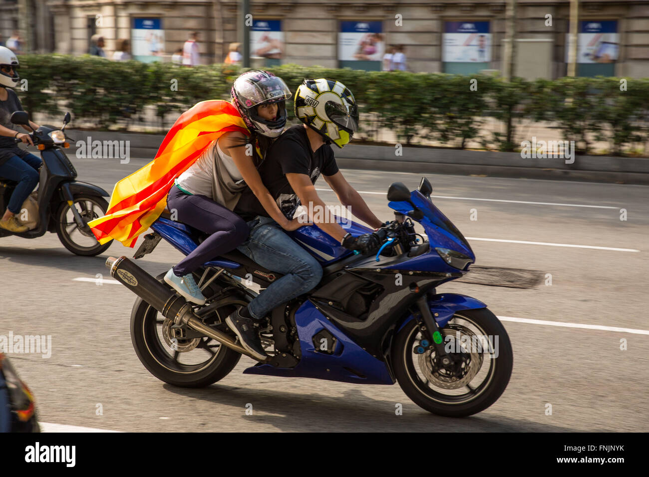 Sep 11, 2015 - Barcellona, Spagna - ragazza indossa una bandiera con orgoglio mentre riding pillion su una motocicletta come persone marzo indossando la bandiera catalana all'Arc de Triomf di Barcellona. Barcellona è stato un mare di rosso e giallo come la folla portando bandiere separatisti hanno marciato in città per celebrare il catalano Giornata Nazionale. Gli organizzatori spera di attirare almeno mezzo milione di persone per un pro-indipendenza rally usando lo slogan 'cominciamo a costruire un nuovo paese". La Estelada o "Lone Star bandiera" è una Bandiera non ufficiale tipicamente percorse da catalano separatisti per esprimere il loro sostegno ad un organismo indipendente la Catalogna. (Immagine di credito Foto Stock