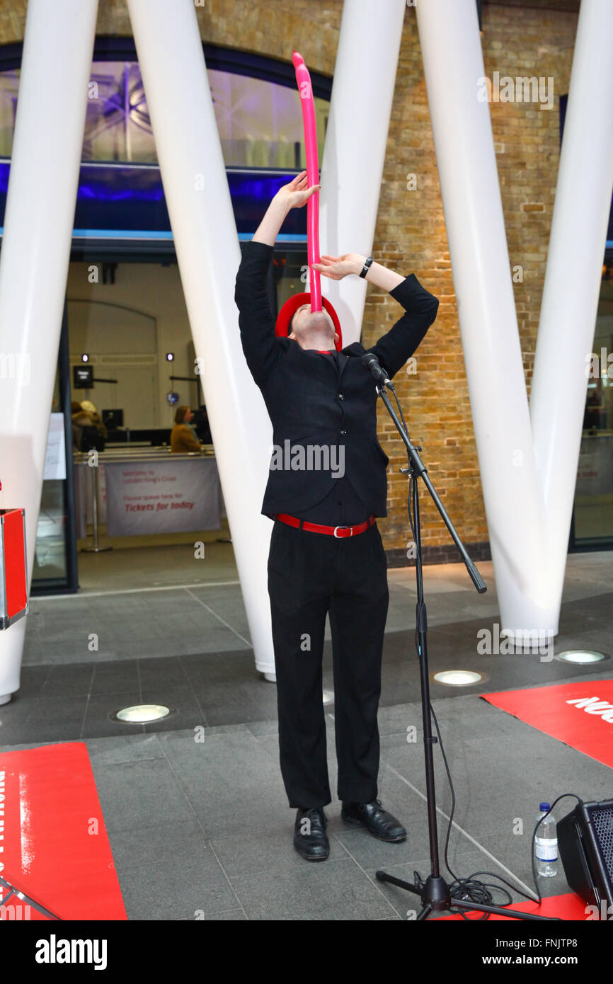 Londra, UK, 16 marzo 2016 - Shaun mira inghiottire un palloncino. Mattina pendolari sono trattati con una varietà unica mostra da musicisti e artisti di strada durante le ore di punta alla stazione di King Cross a il primo al mondo mai International musicista di strada giorno viene annunciato dal sindaco di Londra. Credito: Dinendra Haria/Alamy Live News Foto Stock