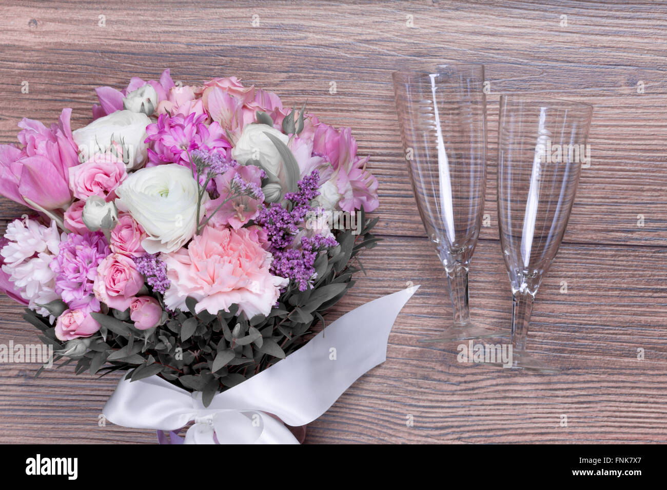 Bicchieri di vino con bouquet di fiori su sfondo di legno Foto Stock