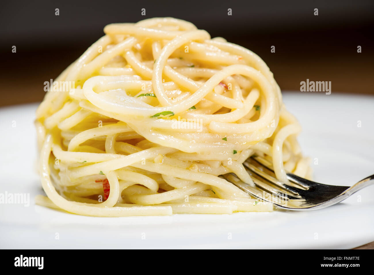 Spaghetti aglio olio e peperoncino con il prezzemolo e la forcella sulla tavola Foto Stock