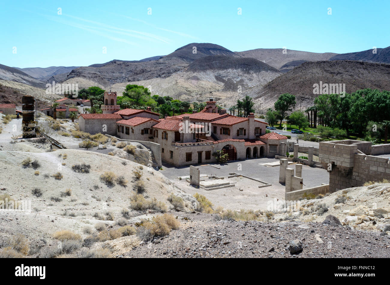 Guardando oltre lo Scotty del castello e parco nazionale della Valle della Morte. Cielo blu, tetti rossi e verdi alberi. Foto Stock