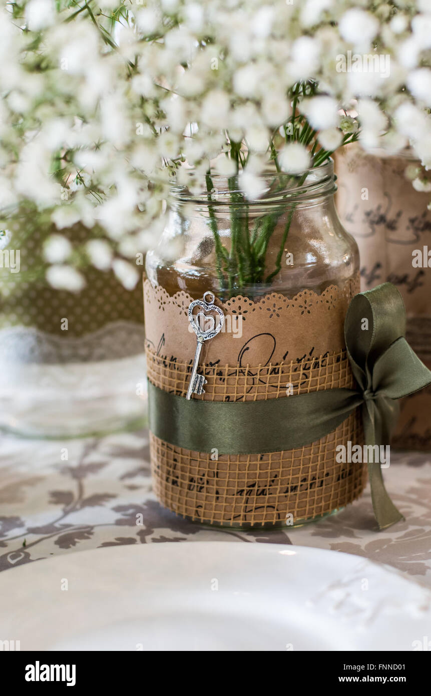 Decorazioni per matrimoni per la tavola, fiori bianchi nel vasetto di vetro, piastra sul primo piano, chiave come un elemento di design Foto Stock