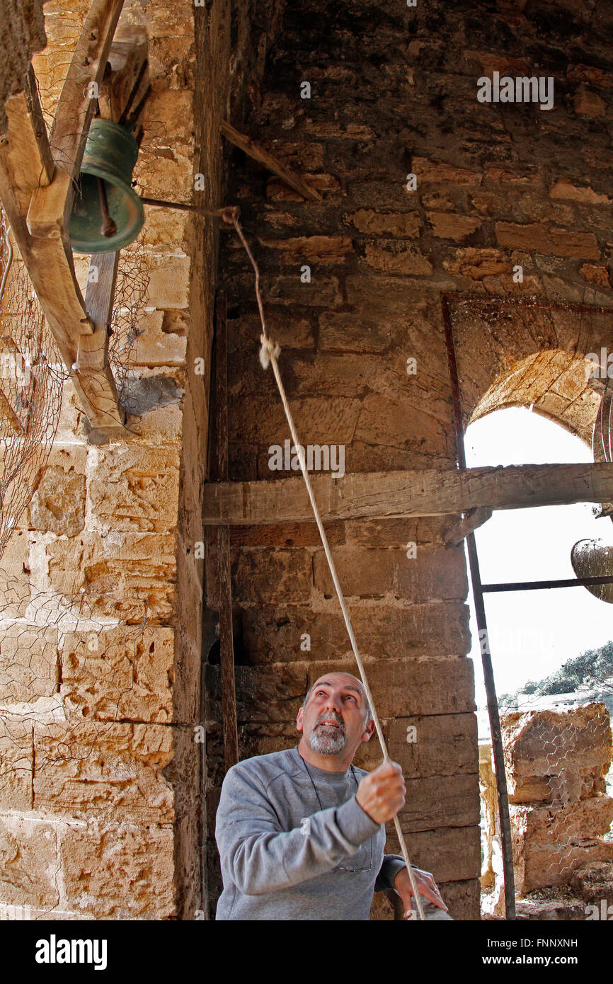 Persona suonare le campane della chiesa. La vecchia chiesa è in un villaggio in Sierra Tramuntana a Maiorca nelle Isole Baleari. Foto Stock