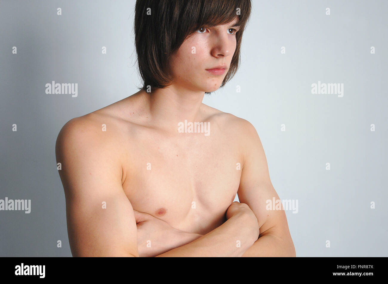 Un bare chested ragazzo adolescente con le sue braccia croce. Foto Stock