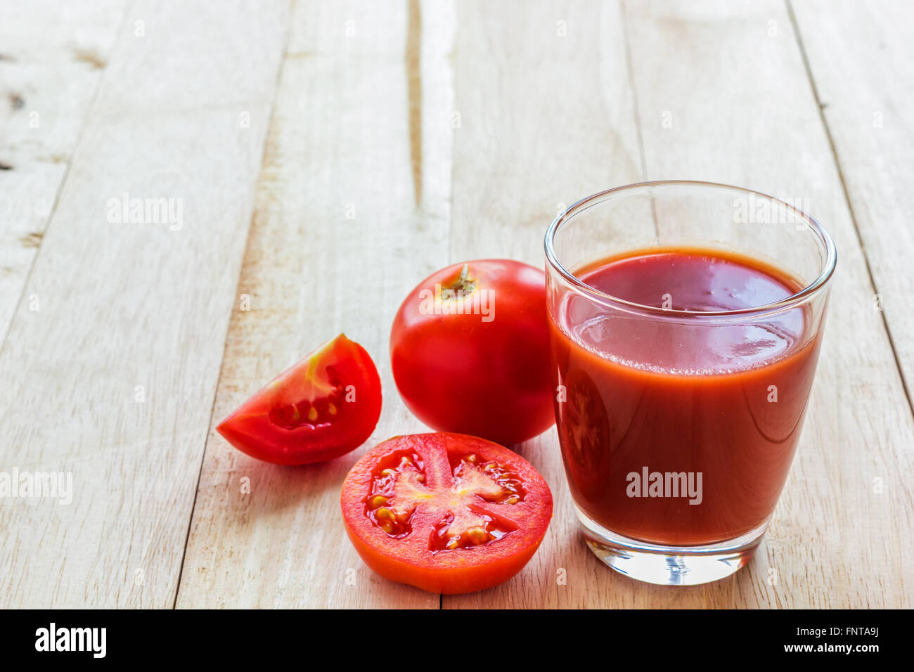 Una foto del succo di pomodoro in vetro sul listone pannello di legno Foto Stock