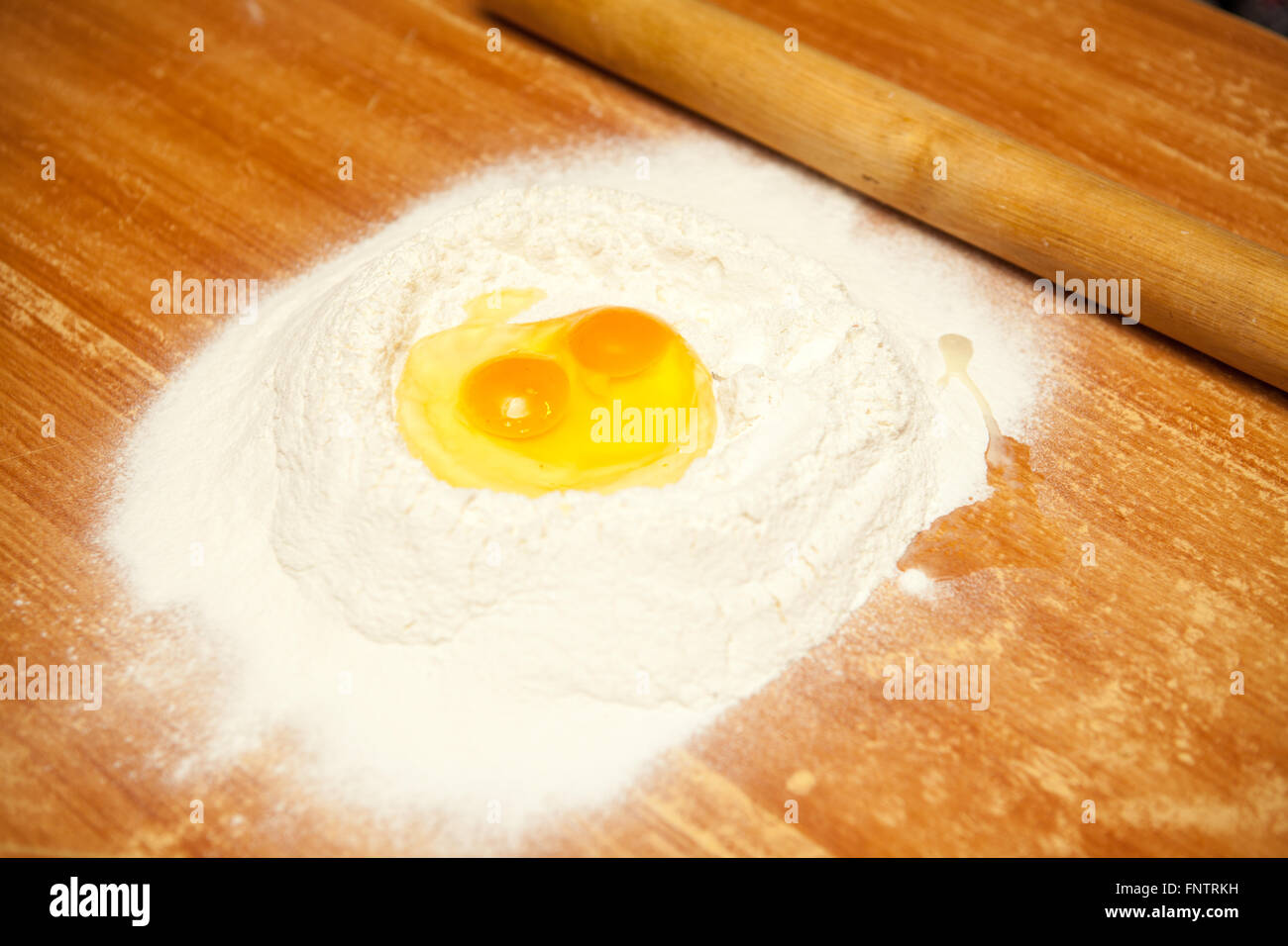 Uova crude nella farina su una tavola di legno Foto Stock