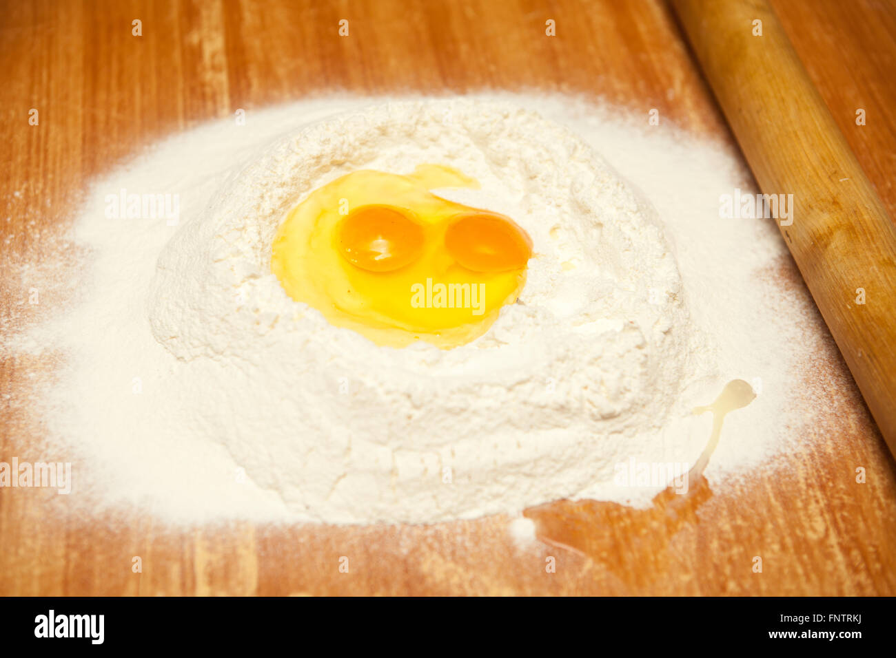 Uova crude nella farina su una tavola di legno Foto Stock