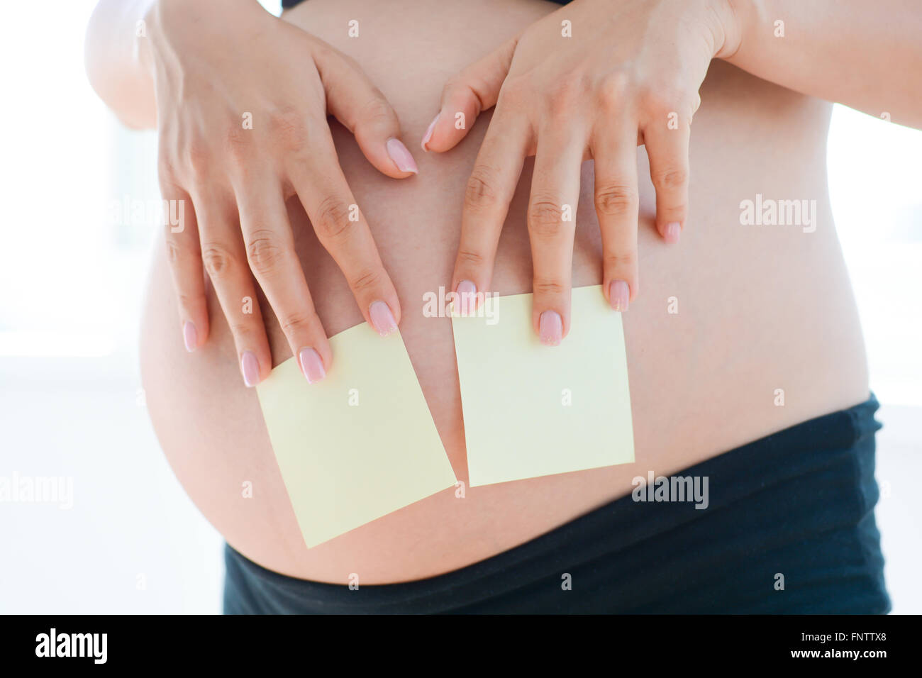 Donna mano distacco vuoto note adesive sulla sua gravidanza pancia Foto Stock