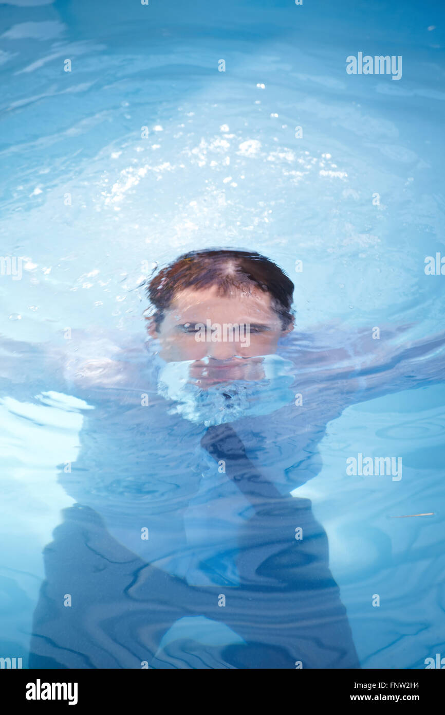 Business man in suit annegamento in oceano con acqua blu Foto Stock