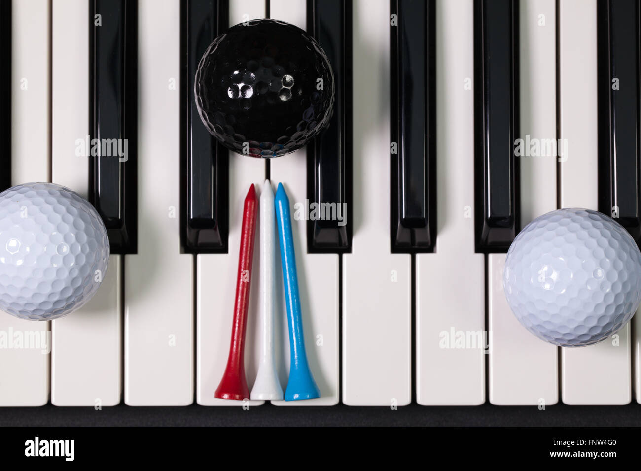 Virtuosi di gioco - Una tastiera di pianoforte e differenti palline da golf e tee di legno Foto Stock