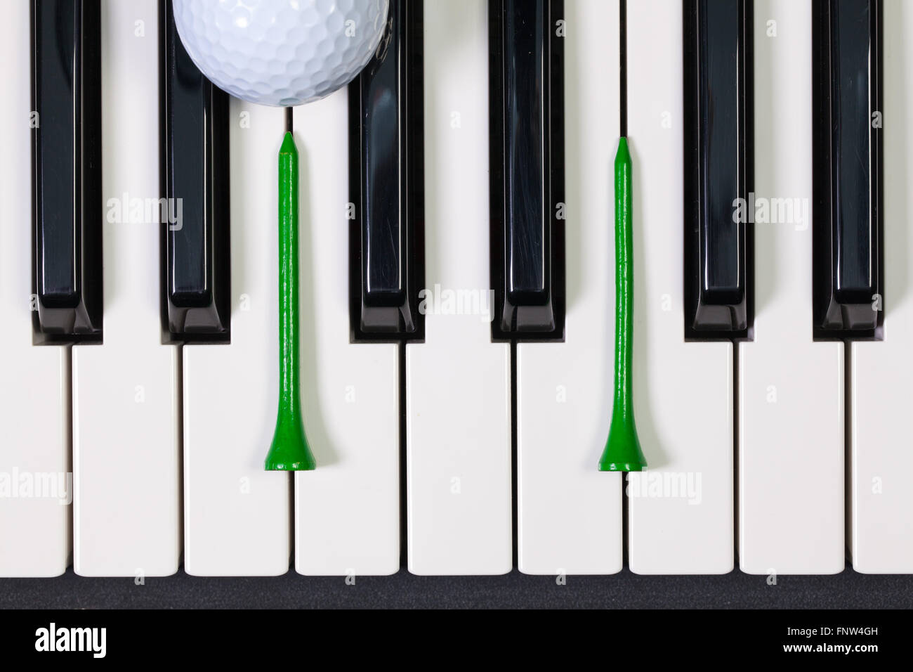 Virtuosi di gioco - Una tastiera di pianoforte e differenti palline da golf e tee di legno Foto Stock