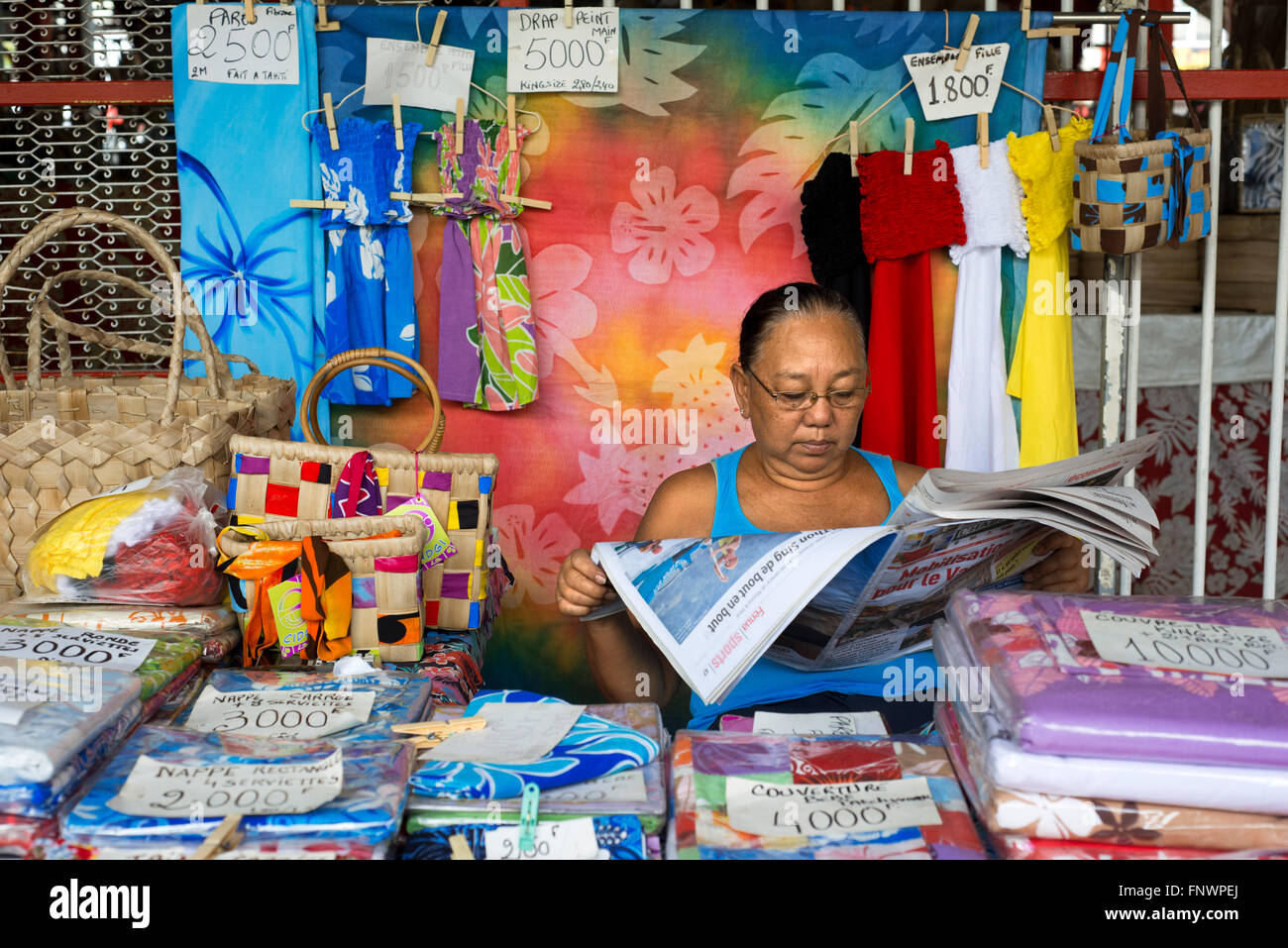 Donna vendita pareu colorati avvolge essendo venduto in un mercato di Papeete sull'isola di Tahiti, Polinesia Francese Tahiti Nui, Soci Foto Stock