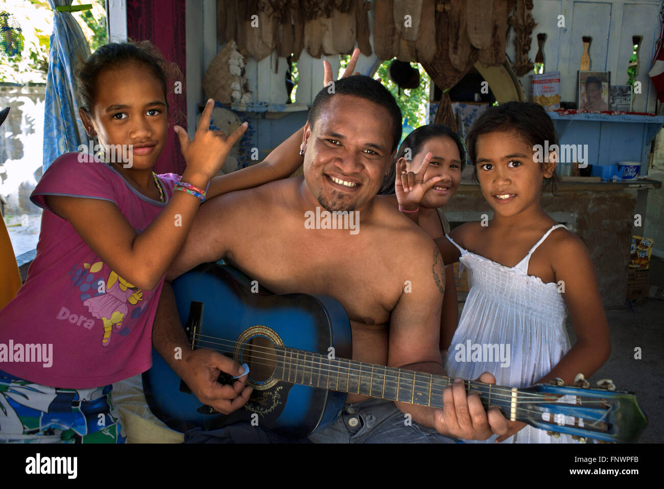Interno di una casa tradizionale in Rangiroa, Tuamotus isole, Polinesia francese, South Pacific. Uomo a suonare la chitarra e singin con Foto Stock
