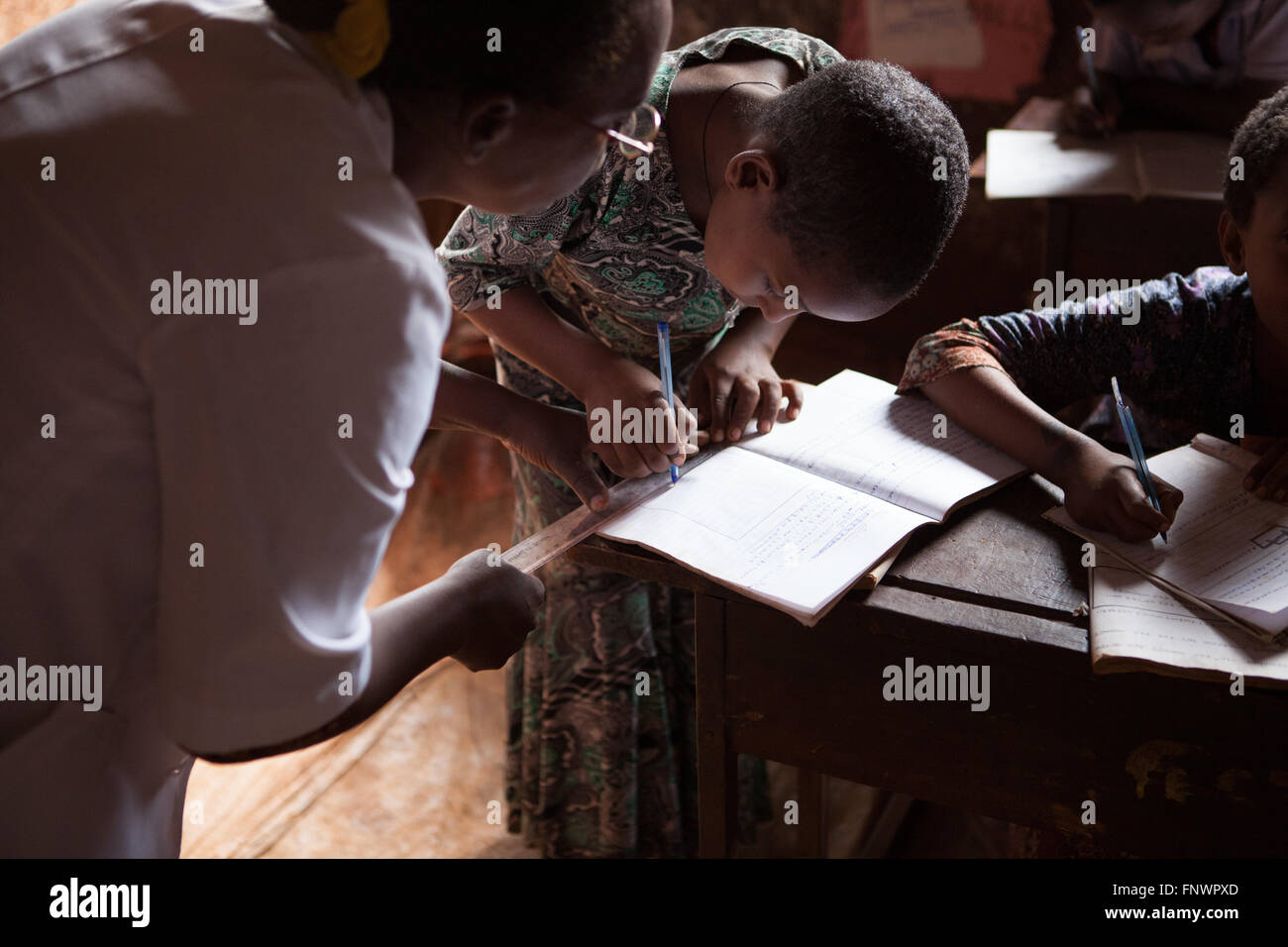 Un insegnante aiuta un alunno con la sua matematica in una scuola, Finote Selam, Etiopia, Africa Foto Stock
