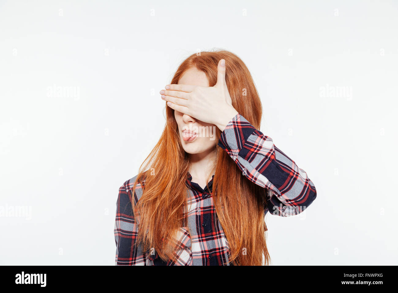 Redhead donna che copre la sua gli occhi e che mostra la linguetta isolata su uno sfondo bianco Foto Stock